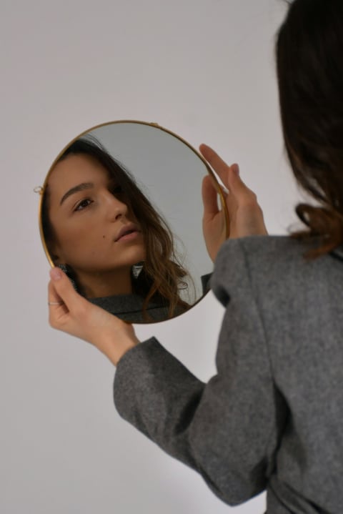 Woman looking at her reflection in a round mirror