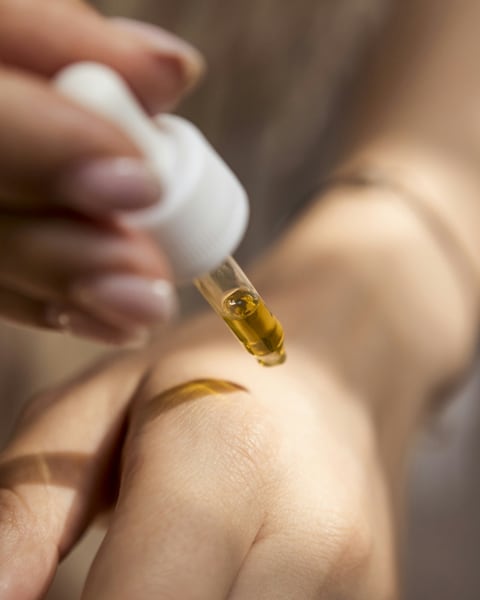 A drop of golden serum on the back of a hand
